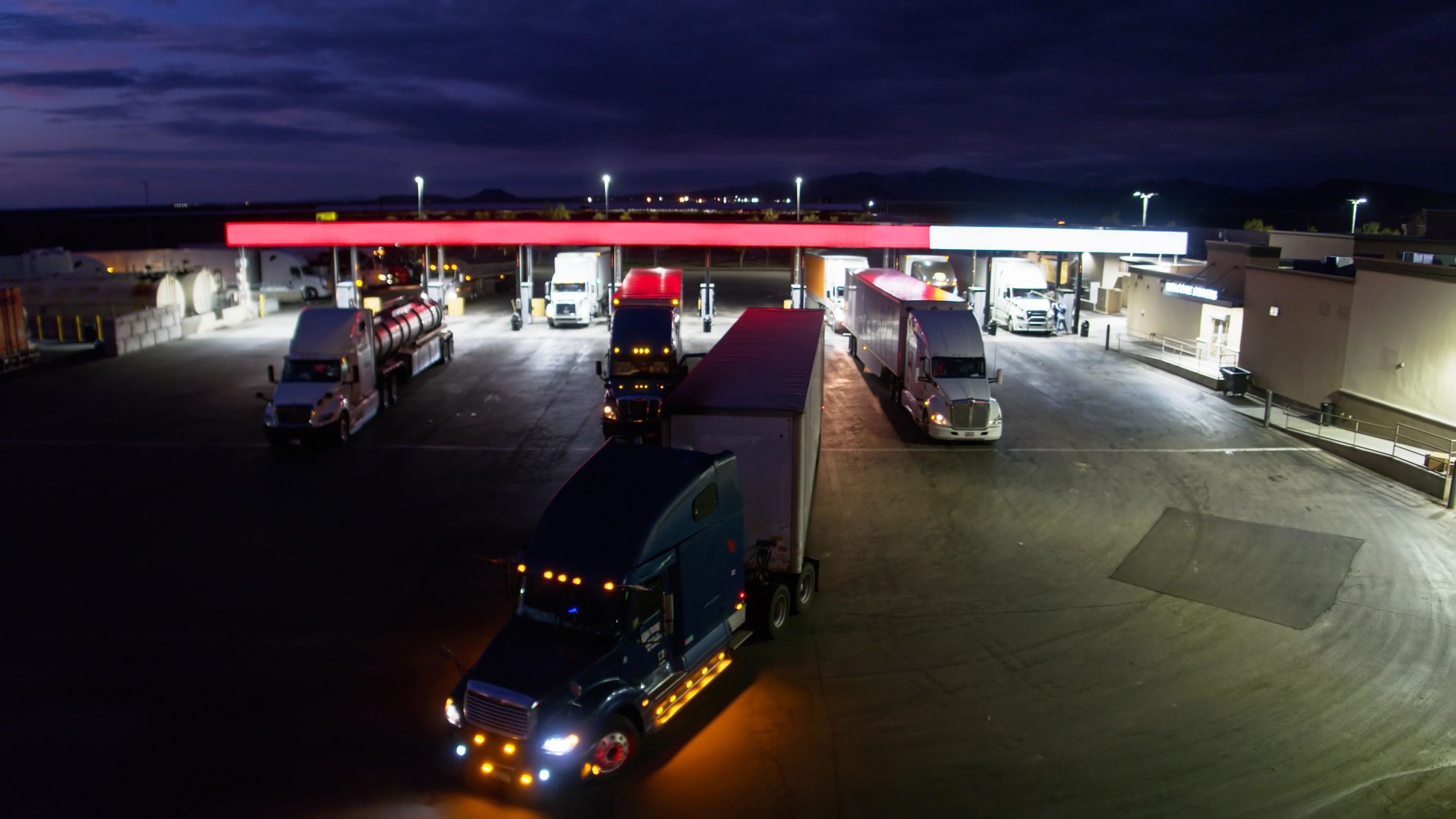 Truck pulling out of gas station at night from aerial view