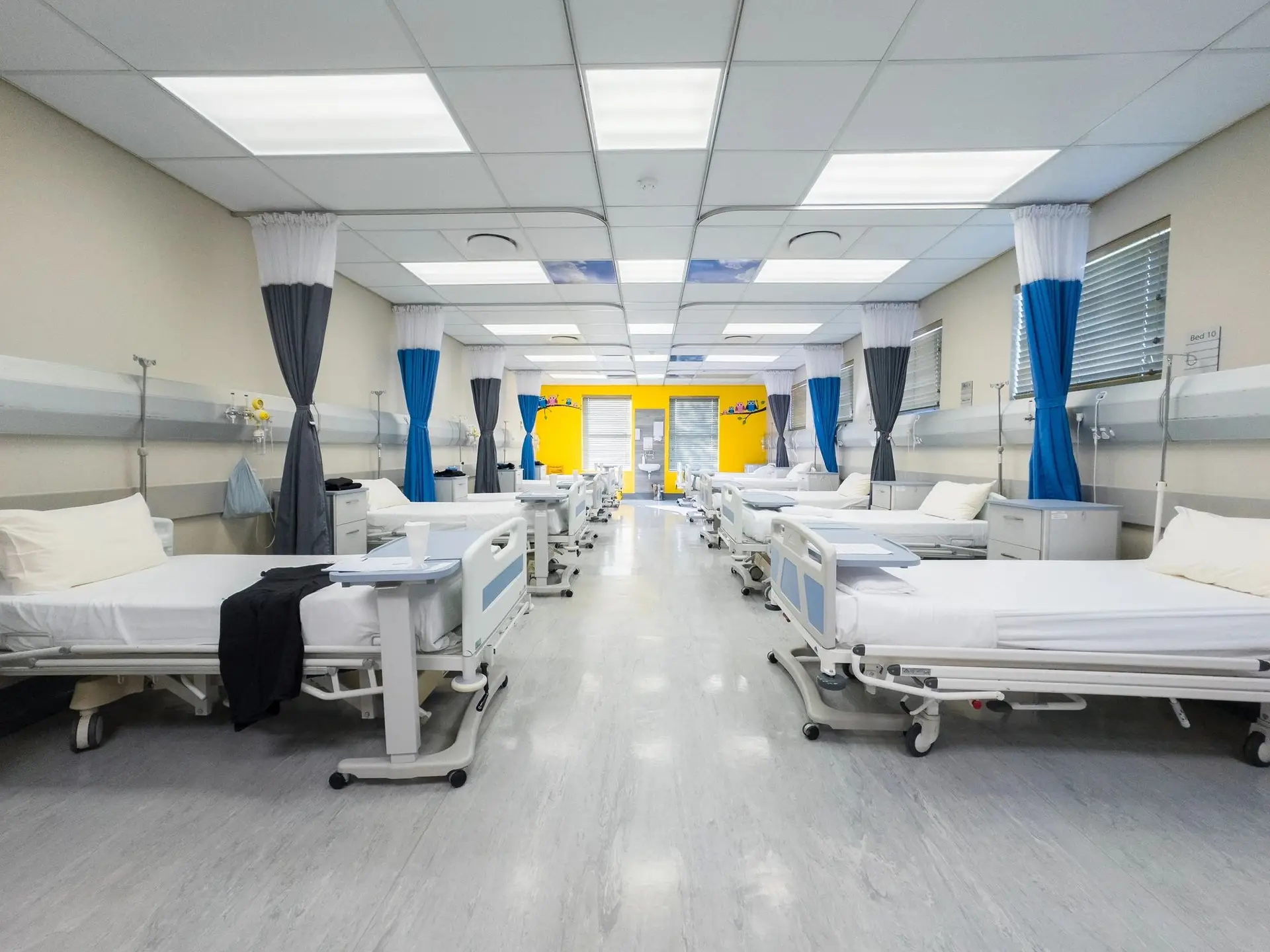 Empty hospital ward with clean floors and prepared beds